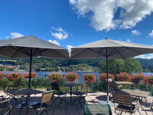 two tables and chairs with umbrellas on a patio at Le Manoir Au Lac in Gérardmer