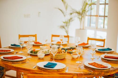 a wooden table with plates of food and wine glasses at Villa Passiflora Zanzibar in Jambiani