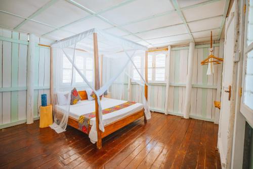 a bedroom with a canopy bed in a room with wooden floors at Villa Passiflora Zanzibar in Jambiani