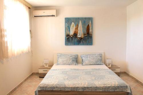a bedroom with a bed with a painting on the wall at Apartments by the sea Sveta Nedilja, Hvar - 110 in Sveta Nedelja