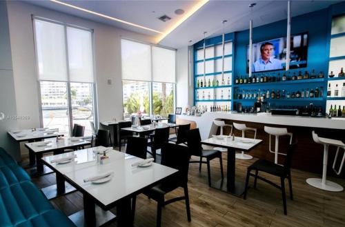 a restaurant with tables and chairs and a bar at Miami Beach Glam, Ocean Views & Elegance -28B in Hallandale Beach
