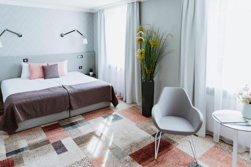 a bedroom with a bed and a chair and a vase of flowers at Pałac Łebunia in Łebunia