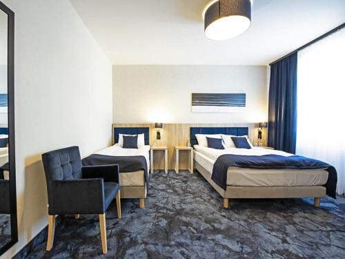 a hotel room with two beds and a chair at Ignasiak Hotel in Września