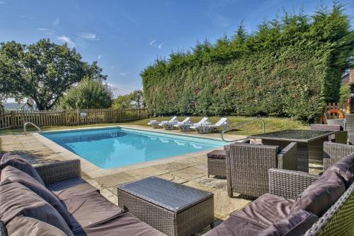 a swimming pool with wicker chairs and a table at Timberley Farm by Group Retreats in Pulborough
