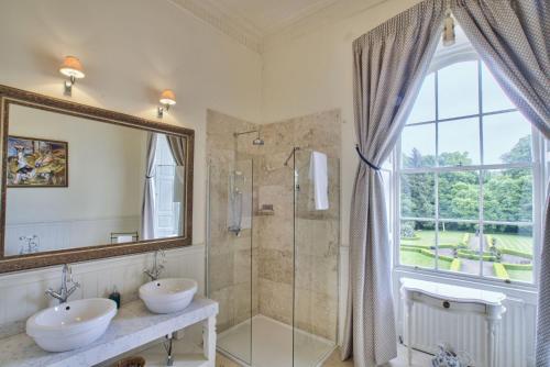 哈特爾浦的住宿－The Castle By Group Retreats，一间带两个盥洗盆和淋浴的浴室以及窗户。