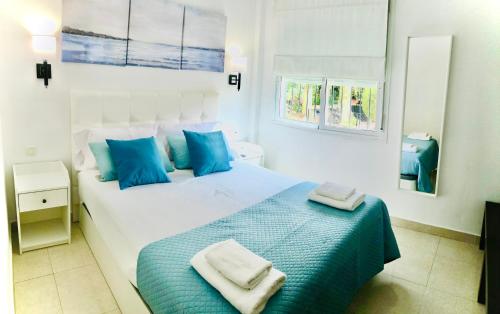 a bedroom with a large white bed with blue pillows at Nuestro Rincón en la Playa, Golf y Piscina driver in Torre de Benagalbón