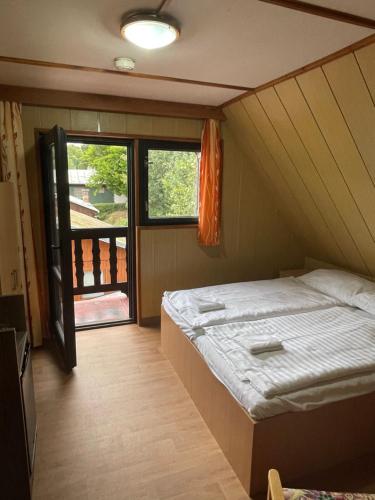 Cette petite chambre comprend un lit et une fenêtre. dans l'établissement Chata Lucka, à Bítov