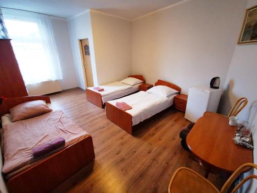 a small room with two beds and a table at Hotel Stary Ratusz in Kostomłoty