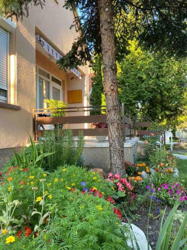 a park bench in front of a building with flowers at Két szobás, teraszos, kertes vendégház in Balatonmáriafürdő