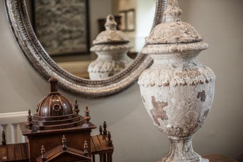 a large white vase sitting on a table in front of a mirror at The Slaughters Manor House in Lower Slaughter
