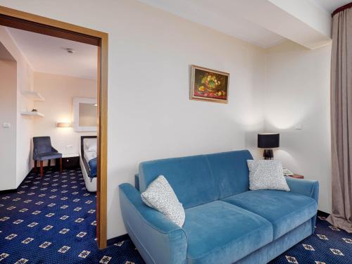 a living room with a blue couch and a mirror at Hotel Liptakówka in Białka Tatrzanska