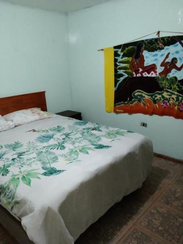a bedroom with a bed with a painting on the wall at Kyea Inn in Hanga Roa