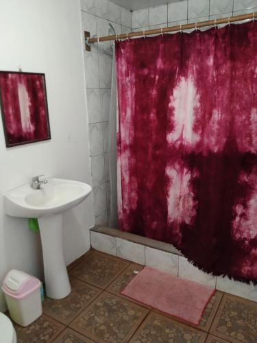 a bathroom with a sink and a red shower curtain at Kyea Inn in Hanga Roa