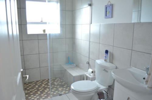 a white bathroom with a toilet and a sink at 24 on Karee in Stilbaai