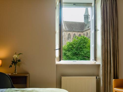 a bedroom window with a view of a church at Romantik Hotel-Restaurant Altenberger Hof in Odenthal
