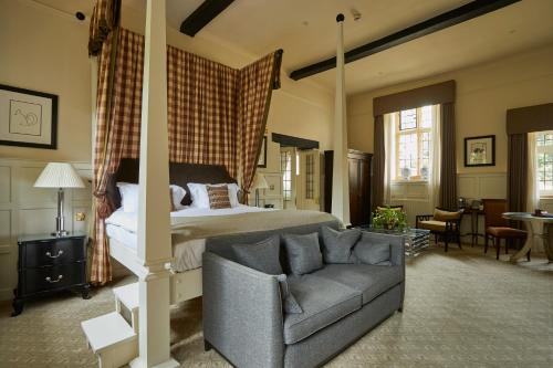 a bedroom with a bed and a couch and a chair at The Slaughters Manor House in Lower Slaughter