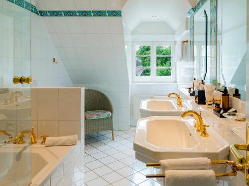 ein weißes Badezimmer mit zwei Waschbecken und einer Badewanne in der Unterkunft Romantikhotel Altenberger Hof in Odenthal