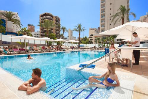 a man and a woman sitting in a swimming pool at Hotel RH Royal - Adults Only in Benidorm