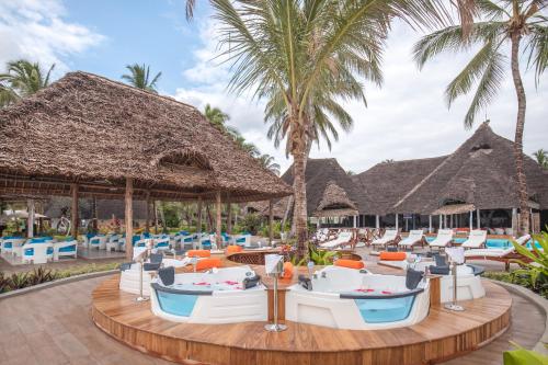 a resort with chairs and tables and palm trees at Kiwengwa Beach Resort in Kiwengwa