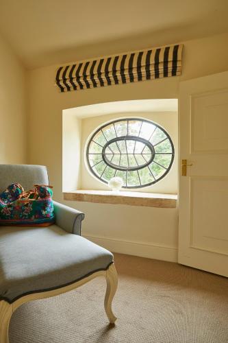 a room with a window with a chair and a window at The Slaughters Manor House in Lower Slaughter