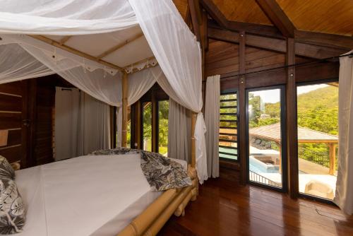 1 dormitorio con 1 cama en una habitación con ventanas en Karucoco lodge, en Deshaies