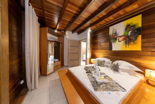 1 dormitorio con 1 cama grande y paredes de madera en Karucoco lodge, en Deshaies