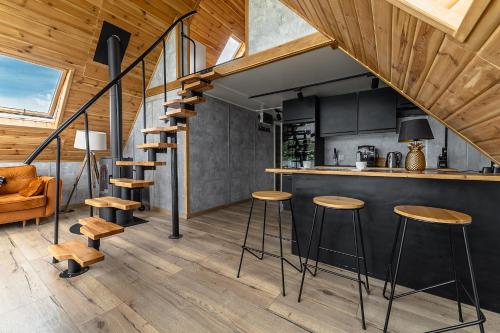 a kitchen and living room with black cabinets and wooden ceilings at Domek na Wodzie FM - Czarna perła in Mrągowo