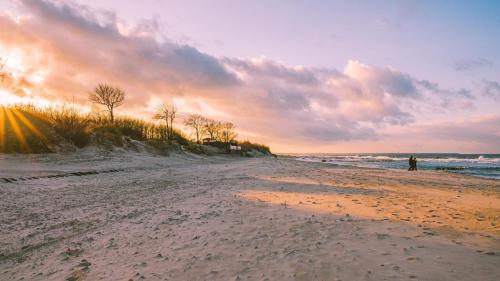 una persona in piedi su una spiaggia al tramonto di Fewo Krysik Unterdeck a Lühmannsdorf