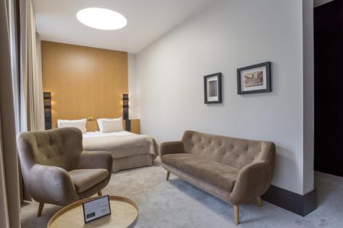 une chambre d'hôtel avec un lit et deux chaises dans l'établissement Hotel Nihil Novi, à Radom