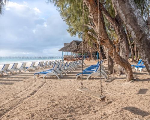 a row of chairs and trees on a beach at Kiwengwa Beach Resort in Kiwengwa