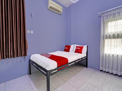 1 dormitorio con 1 cama con almohadas rojas y blancas en OYO Life 91592 Aaliya Guest House Syariah, en Lebakwangi