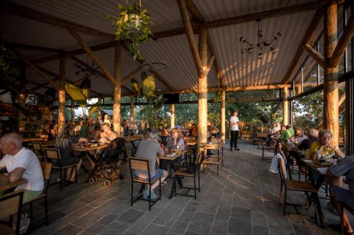 un grupo de personas sentadas en mesas en un restaurante en Lake Shkodra Resort, en Grilë