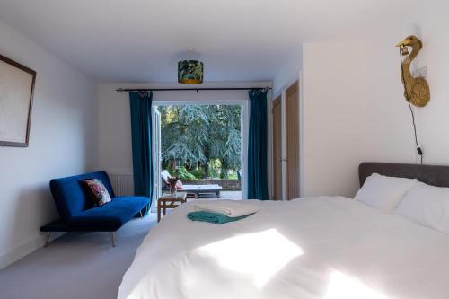 a bedroom with a bed and a blue chair and a window at Furzedown Farm House in Hythe