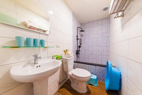 La salle de bains est pourvue d'un lavabo blanc et de toilettes. dans l'établissement LoveBaby Homestay, à Luodong