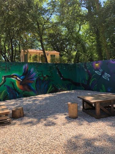 a picnic table and a wall with a mural at Les Mazets de la Cascade in Salernes