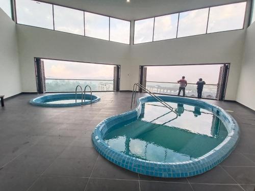 two men standing in a large room with two hot tubs at Homestay at Palas Horizon with sunrise view in Brinchang