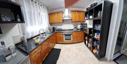 a kitchen with wooden cabinets and a black refrigerator at Carrio appartement 2 chambres in Calpe