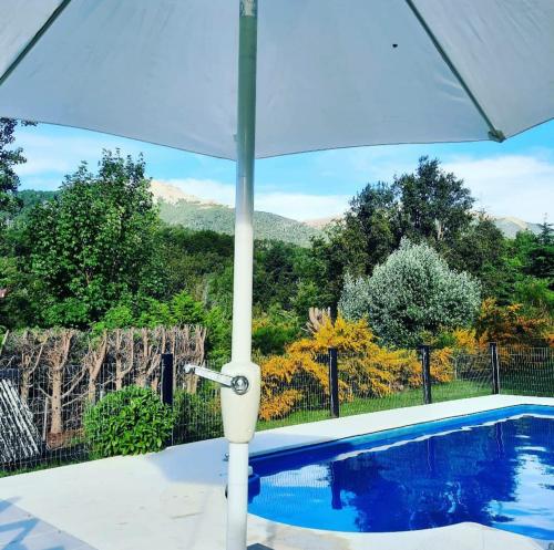 an umbrella over a swimming pool with mountains in the background at Cabañas La Pampita in Villa La Angostura