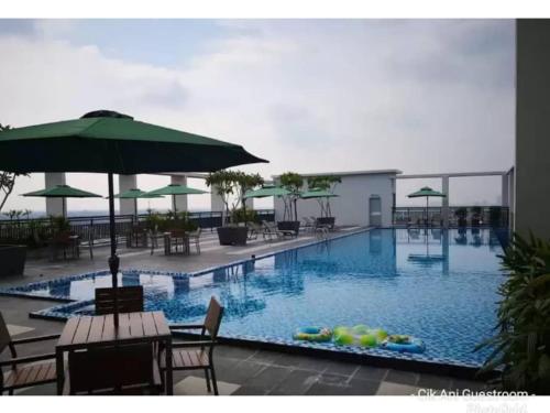 a large swimming pool with chairs and an umbrella at UMMI GUESTROOM in Kota Bharu