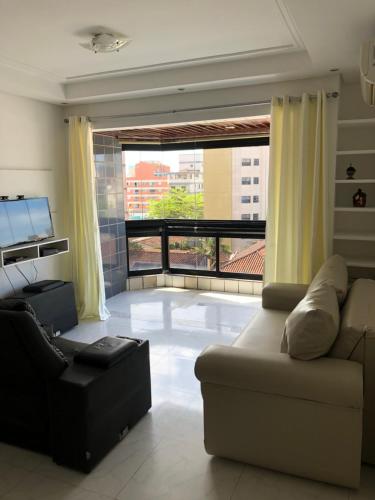 - un salon avec un canapé et une grande fenêtre dans l'établissement Apartamento com Varanda e Suíte Enseada Guarujá, à Guarujá