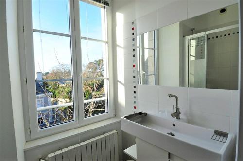 une salle de bain blanche avec un lavabo et une fenêtre dans l'établissement Saint Malo Solidor vue mer BRECEL 1, à Saint-Malo