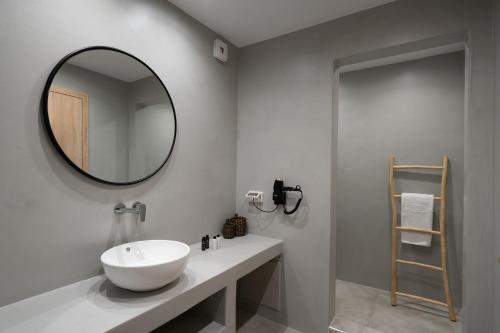 een badkamer met een witte wastafel en een spiegel bij El Destino Suites in Akrotiri