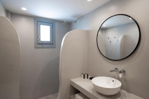a white bathroom with a sink and a mirror at El Destino Suites in Akrotiri