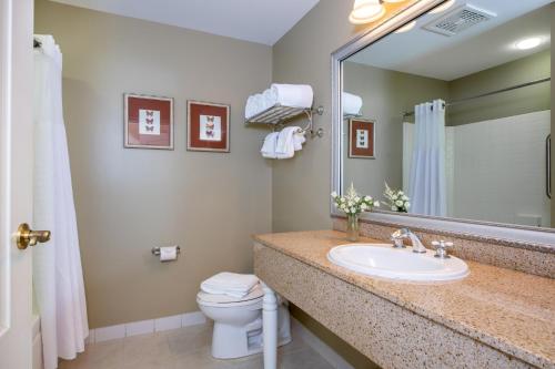 a bathroom with a sink and a toilet and a mirror at Bar Harbor Grand Hotel in Bar Harbor