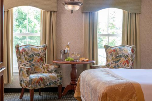 a hotel room with a bed and a table and chairs at Bar Harbor Grand Hotel in Bar Harbor