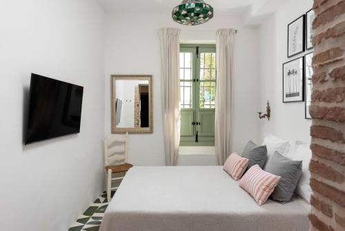a white bedroom with a bed and a tv at La AMARA Farah - en el casco antiguo de Frigiliana in Frigiliana