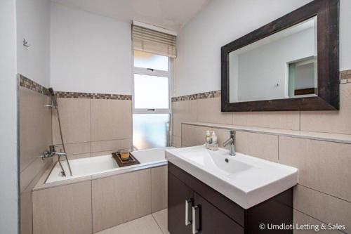 a bathroom with a sink and a tub and a mirror at Sugar Crest 3B with inverter in Umdloti
