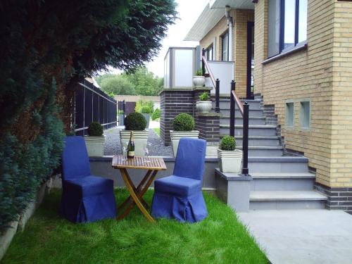 eine Terrasse mit zwei blauen Stühlen, einem Tisch und einer Treppe in der Unterkunft Apartment Capitalcondos in Ninove