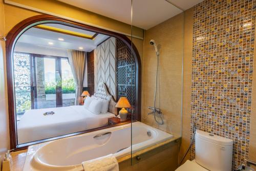 a bathroom with a tub and a bed and a bed and a toilet at Boutik Cham NhaTrang Hotel in Nha Trang