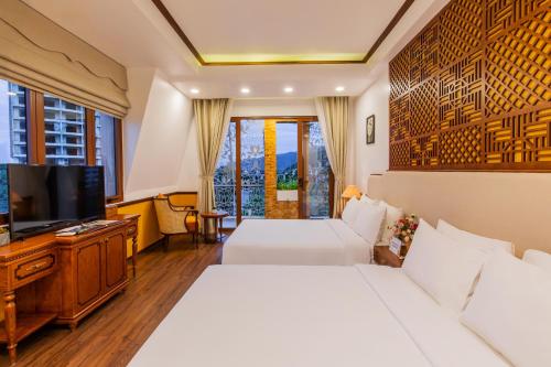 Boutik Cham NhaTrang Hotel في نها ترانغ: غرفة فندقية بسريرين وتلفزيون بشاشة مسطحة